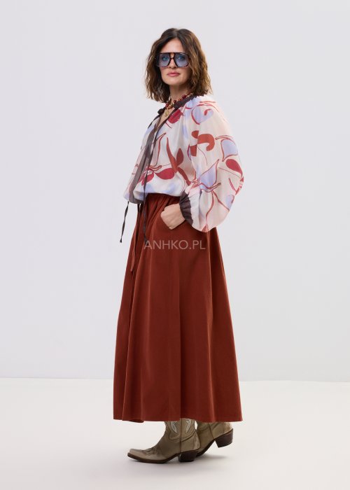 Bluzka damska z lekkiej, półtransparentnej tkaniny z abstrakcyjnym wzorem w odcieniach kremowym i czerwieni, z wiązaniem przy dekolcie i długimi rękawami.