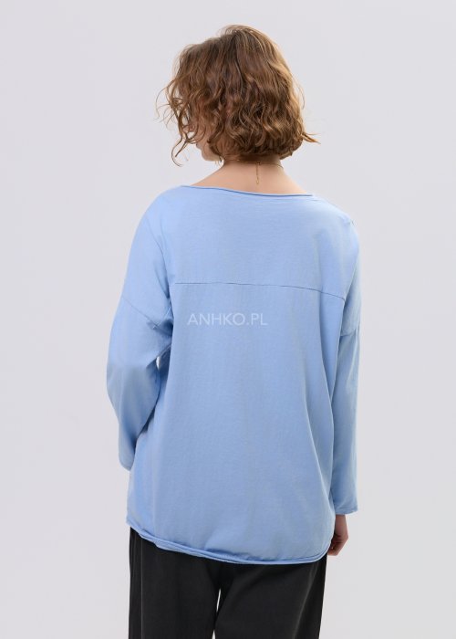 Niebieska bluzka damska oversize z haftowanym wzorem kwiatowym, z długim rękawem i szerokim dekoltem, stylizowana z czarnymi spodniami.