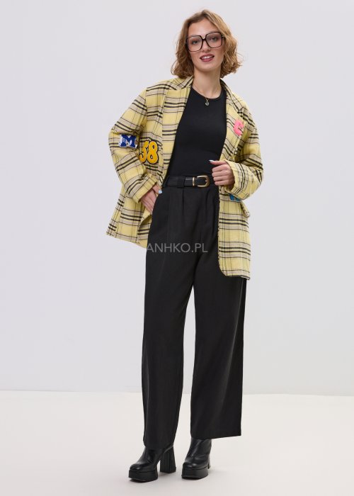 Marynarka damska w żółtą kratę z kolorowymi naszywkami literowymi, o luźnym kroju z klapami, stylizowany z czarnym topem i spodniami.