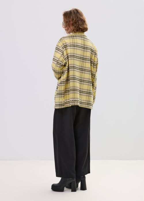 Marynarka damska w żółtą kratę z kolorowymi naszywkami literowymi, o luźnym kroju z klapami, stylizowany z czarnym topem i spodniami.