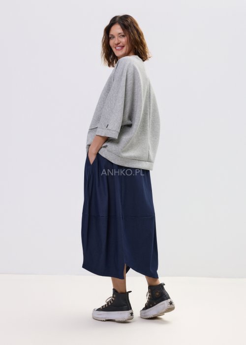 Szara bluza damska oversize z krótkim rękawem typu kimono i asymetrycznym dołem, wykonana z miękkiej dzianiny, stylizowana ze spódnicą.