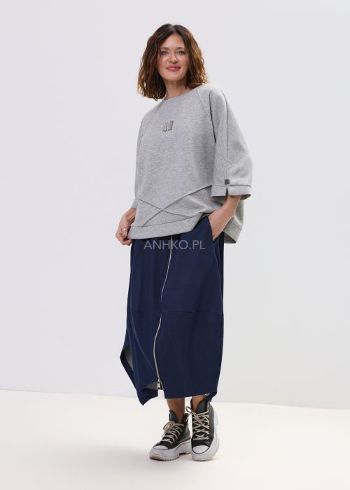 Szara bluza damska oversize z krótkim rękawem typu kimono i asymetrycznym dołem, wykonana z miękkiej dzianiny, stylizowana ze spódnicą.
