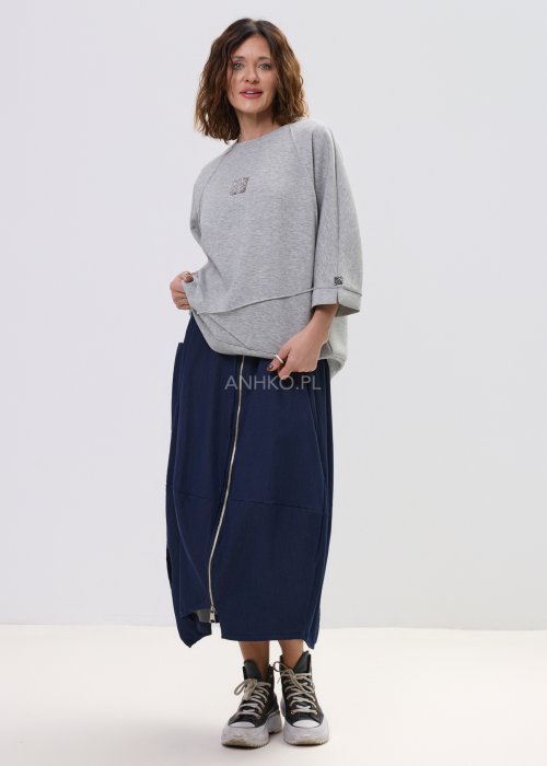 Szara bluza damska oversize z krótkim rękawem typu kimono i asymetrycznym dołem, wykonana z miękkiej dzianiny, stylizowana ze spódnicą.