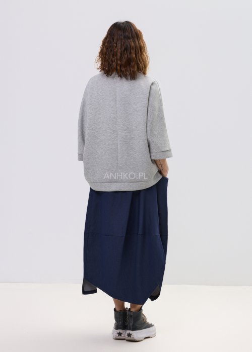 Szara bluza damska oversize z krótkim rękawem typu kimono i asymetrycznym dołem, wykonana z miękkiej dzianiny, stylizowana ze spódnicą.