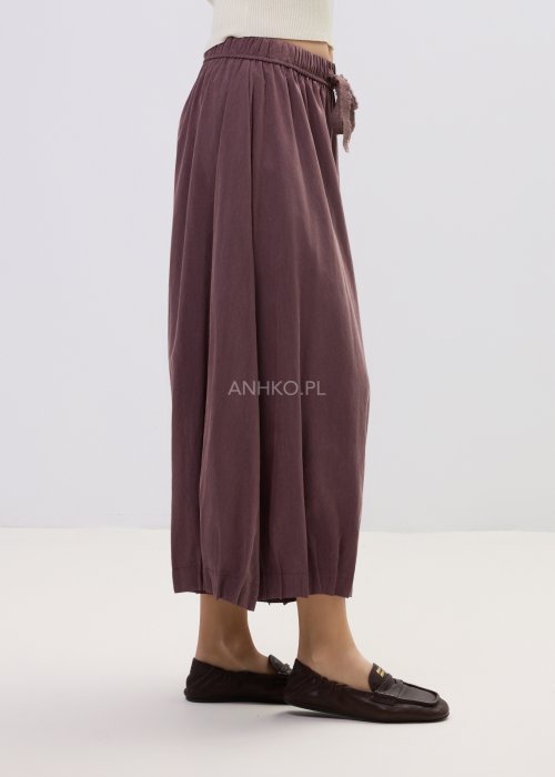 Spodnie damskie typu culotte w kolorze wina z szeroką nogawką i gumką w pasie, luźny fason z marszczeniem i wiązaniem w casualowej stylizacji.