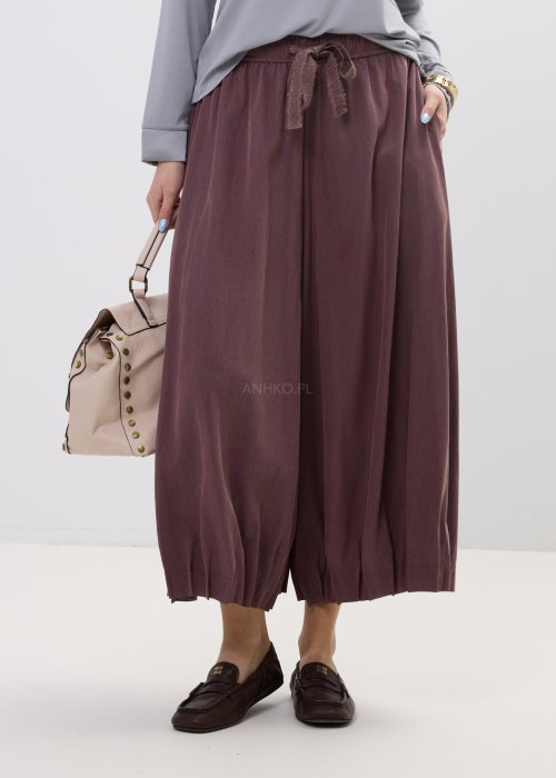 Spodnie damskie typu culotte w kolorze wina z szeroką nogawką i gumką w pasie, luźny fason z marszczeniem i wiązaniem w casualowej stylizacji.