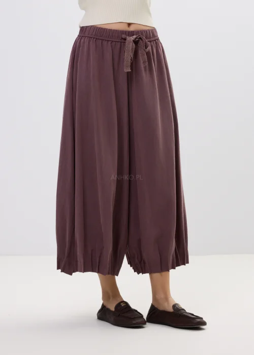 Spodnie damskie typu culotte w kolorze wina z szeroką nogawką i gumką w pasie, luźny fason z marszczeniem i wiązaniem w casualowej stylizacji.