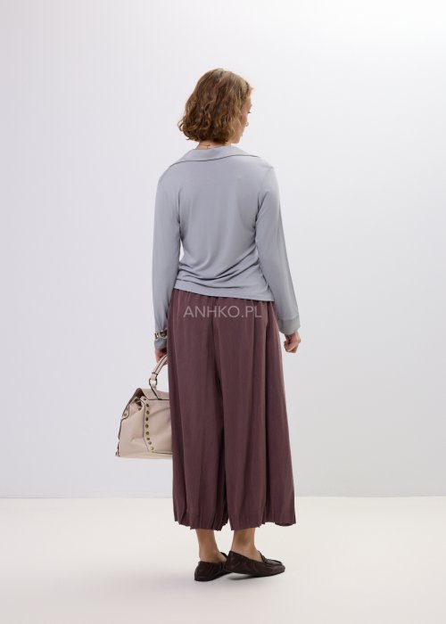 Szara bluzka damska z długim rękawem i dekoltem, o dopasowanym kroju, zestawiona z luźnymi spodniami w odcieniu brązu w stylu casual.