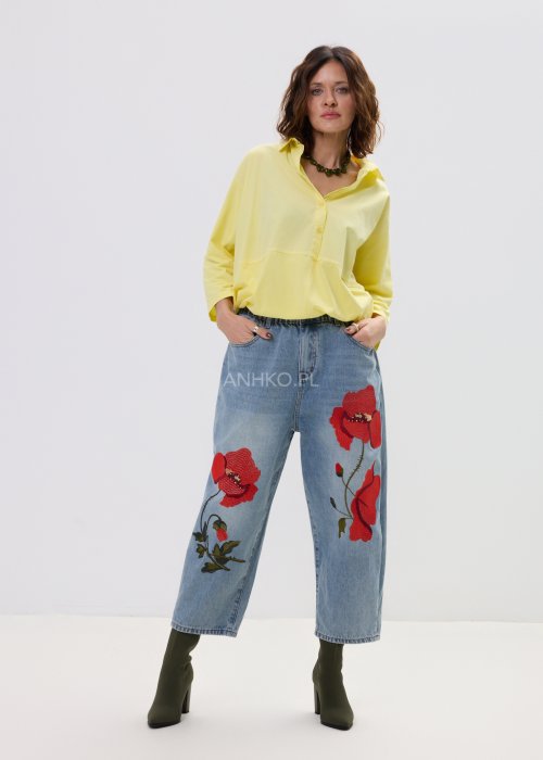 Żółta koszula damska oversize z kołnierzykiem i dekoltem polo, o luźnym kroju z długim rękawem, zestawiona z jeansami w stylu casual.