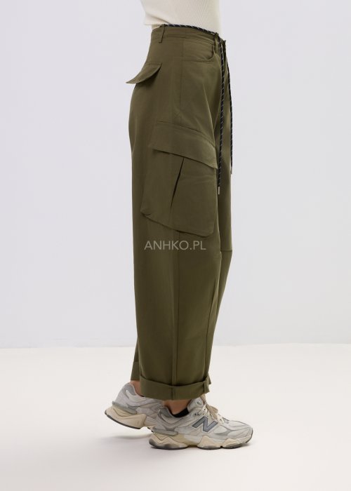 Spodnie damskie cargo khaki z wysokim stanem, szeroką nogawką i dużymi kieszeniami bocznymi, wykończone paskiem ze sznurkiem, stylizowane ze sneakersami.