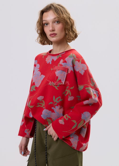 Czerwona bluza damska w kwiaty o luźnym kroju z długim rękawem i kieszonką na piersi, zestawiona z oliwkowymi spodniami w stylu casual.
