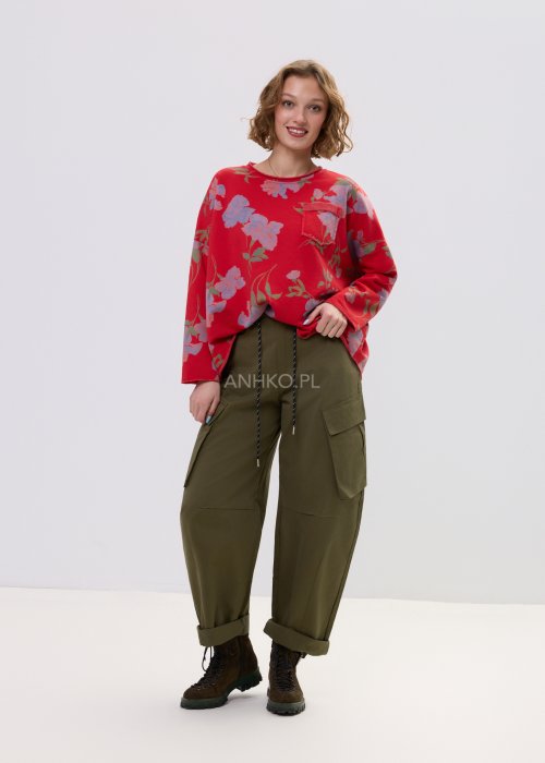Czerwona bluza damska w kwiaty o luźnym kroju z długim rękawem i kieszonką na piersi, zestawiona z oliwkowymi spodniami w stylu casual.