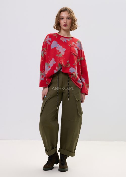 Czerwona bluza damska w kwiaty o luźnym kroju z długim rękawem i kieszonką na piersi, zestawiona z oliwkowymi spodniami w stylu casual.