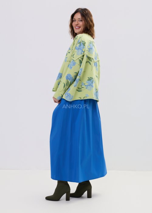 Zielona bluza damska w niebieskie kwiaty o luźnym kroju z długim rękawem i kieszonką na piersi, zestawiona z niebieską spódnicą w stylu casual.