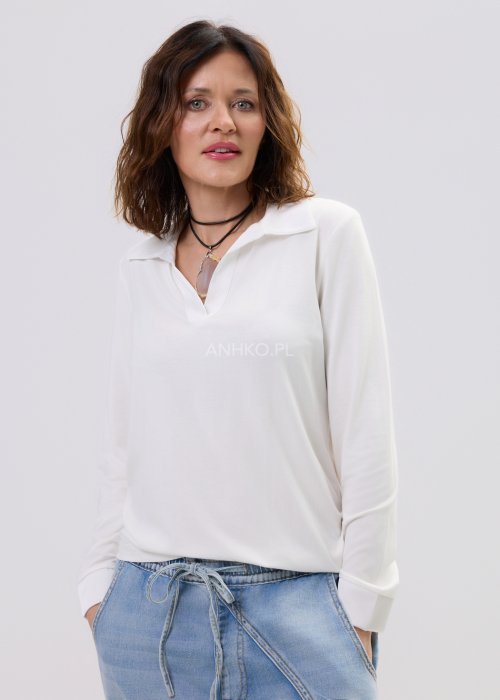 Biała bluzka damska z długim rękawem i dekoltem w stylu polo, o gładkim wykończeniu, zestawiona z jasnymi jeansami w casualowej stylizacji.