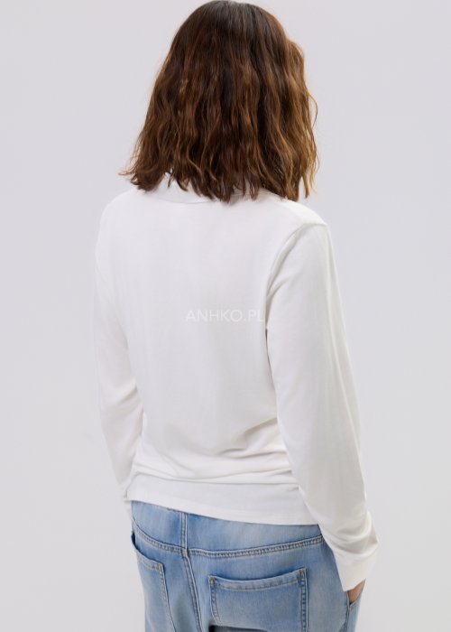 Biała bluzka damska z długim rękawem i dekoltem w stylu polo, o gładkim wykończeniu, zestawiona z jasnymi jeansami w casualowej stylizacji.