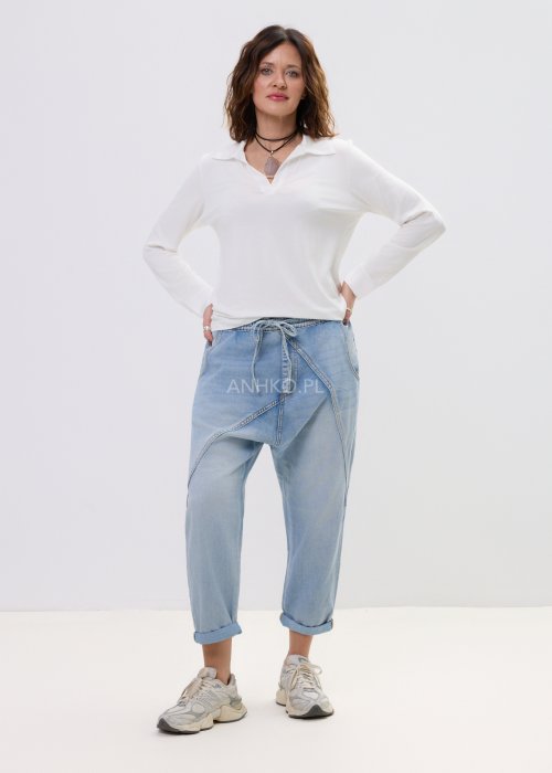 Biała bluzka damska z długim rękawem i dekoltem w stylu polo, o gładkim wykończeniu, zestawiona z jasnymi jeansami w casualowej stylizacji.