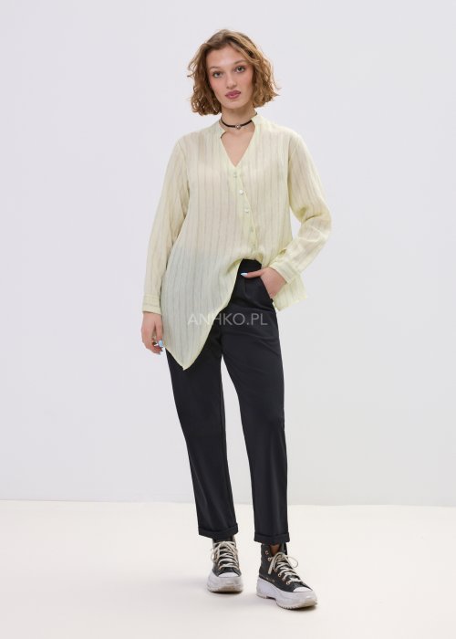 Czarne spodnie damskie z prostą nogawką i elastycznym pasem, o minimalistycznym fasonie, zestawione ze sneakersami w codziennej stylizacji.