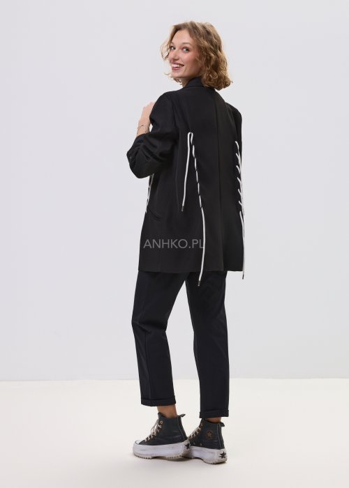 Czarne spodnie damskie z prostą nogawką i elastycznym pasem, o minimalistycznym fasonie, zestawione ze sneakersami w codziennej stylizacji.