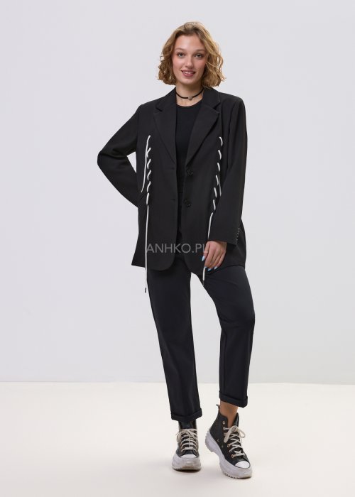 Czarne spodnie damskie z prostą nogawką i elastycznym pasem, o minimalistycznym fasonie, zestawione ze sneakersami w codziennej stylizacji.