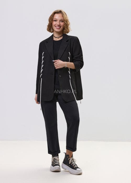 Czarna marynarka damska o prostym kroju z ozdobnymi białymi sznurkami po bokach i z tyłu, zapinana na guziki.