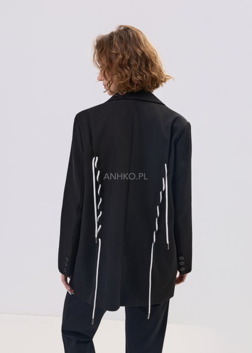 Czarna marynarka damska o prostym kroju z ozdobnymi białymi sznurkami po bokach i z tyłu, zapinana na guziki.