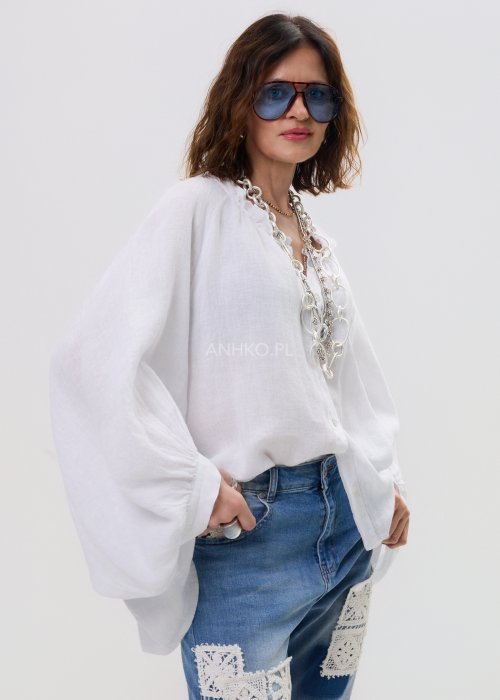 Biała lniana koszula damska oversize z długim rękawem i lekkim, zwiewnym materiałem, stylizowana z jeansami i biżuterią w casualowym looku.