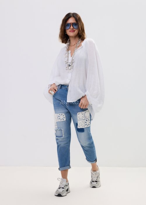 Biała lniana koszula damska oversize z długim rękawem i lekkim, zwiewnym materiałem, stylizowana z jeansami i biżuterią w casualowym looku.