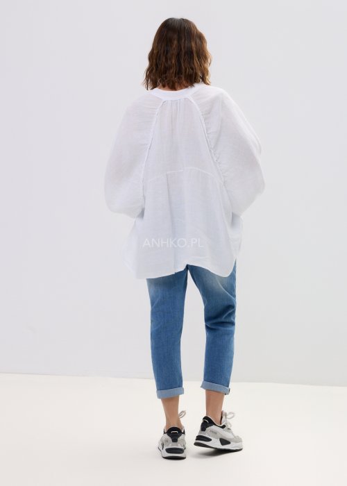 Biała lniana koszula damska oversize z długim rękawem i lekkim, zwiewnym materiałem, stylizowana z jeansami i biżuterią w casualowym looku.