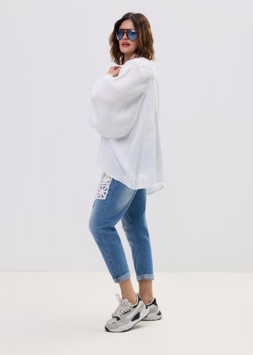 Biała lniana koszula damska oversize z długim rękawem i lekkim, zwiewnym materiałem, stylizowana z jeansami i biżuterią w casualowym looku.