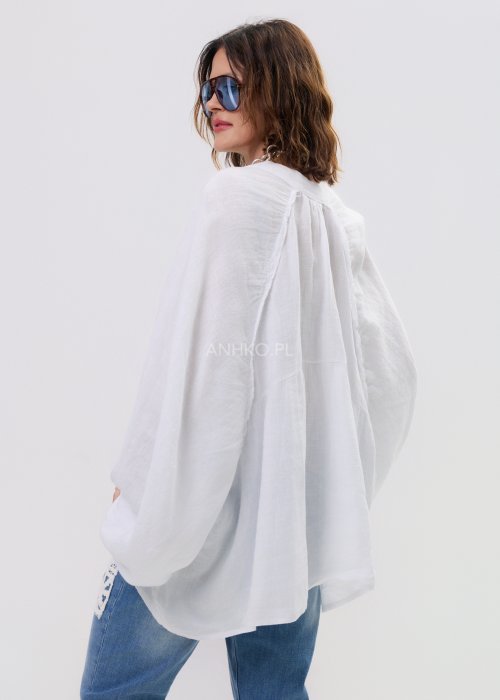 2Biała lniana koszula damska oversize z długim rękawem i lekkim, zwiewnym materiałem, stylizowana z jeansami i biżuterią w casualowym looku.