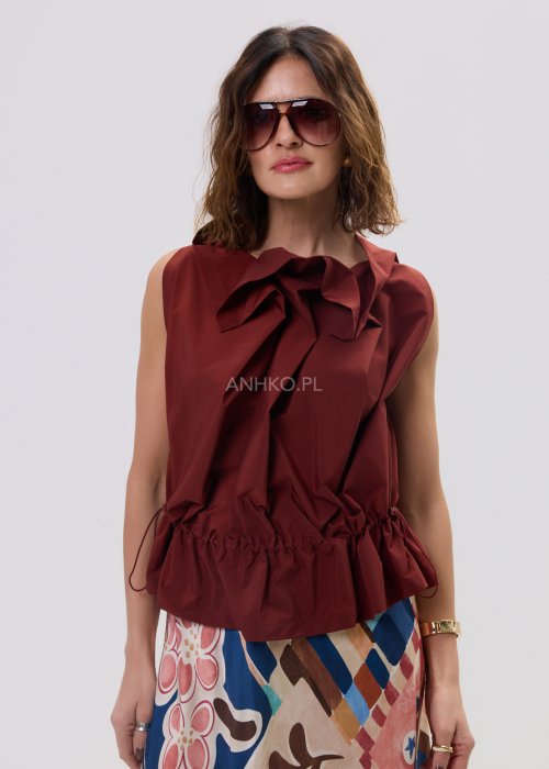 Bluzka bez rękawów w kolorze ceglanym z dekoracyjną falbaną przy dekolcie i marszczeniem w talii – elegancki fason na sylwetce