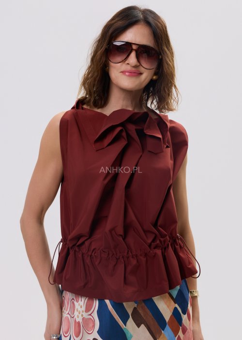 Bluzka bez rękawów w kolorze ceglanym z dekoracyjną falbaną przy dekolcie i marszczeniem w talii – elegancki fason na sylwetce