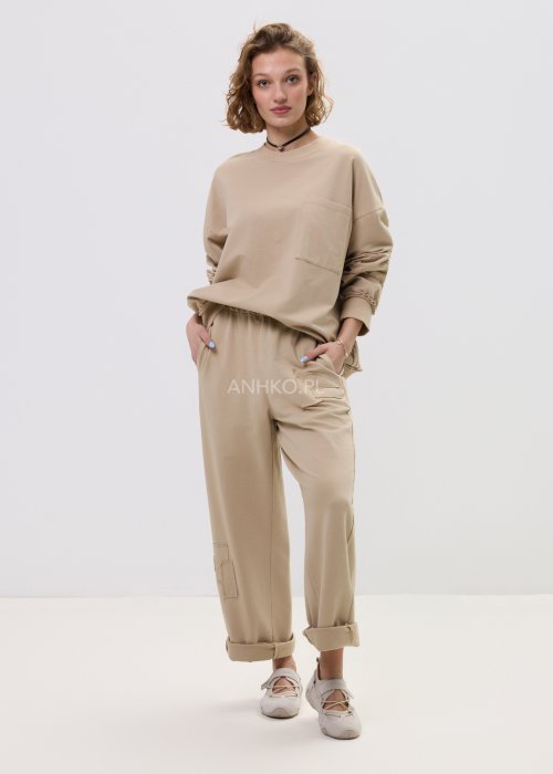 Beżowa bluza damska o luźnym kroju z kieszonką na piersi i długimi rękawami zakończonymi ściągaczem.