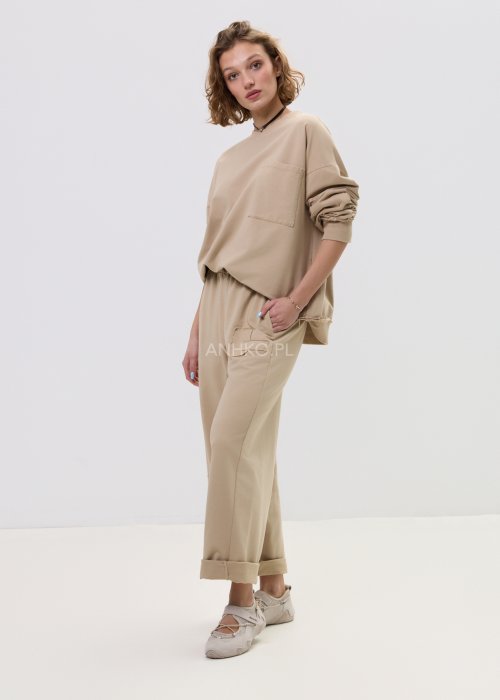 Beżowa bluza damska o luźnym kroju z kieszonką na piersi i długimi rękawami zakończonymi ściągaczem.