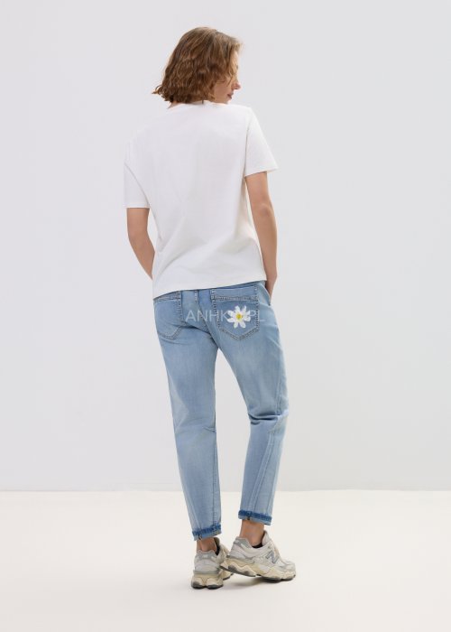 Biała bluzka t-shirt damski z krótkim rękawem i ozdobną kieszonką z ażurową aplikacją w kształcie stokrotki.