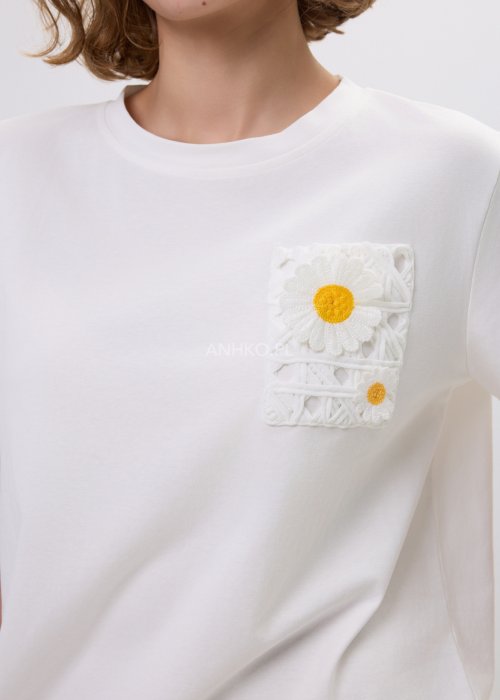 Biała bluzka t-shirt damski z krótkim rękawem i ozdobną kieszonką z ażurową aplikacją w kształcie stokrotki.
