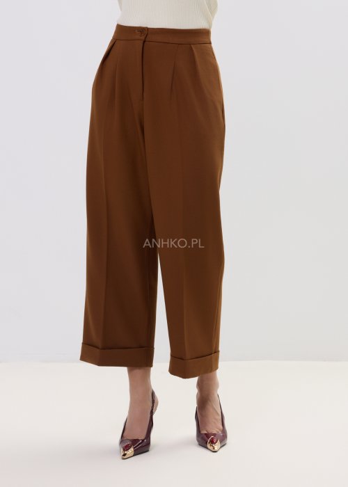 Karmelowe eleganckie spodnie damskie o szerokim kroju z wysokim stanem i podwiniętą nogawką.