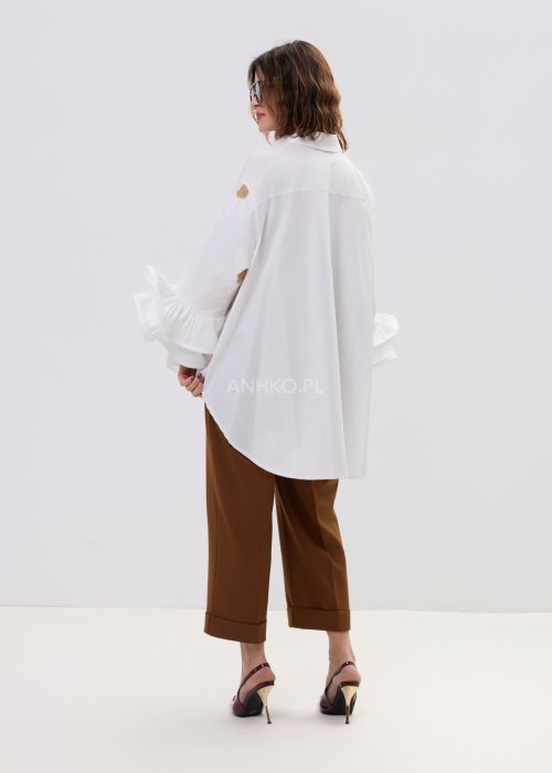 Biała koszula damska oversize z haftowanymi stokrotkami i szerokimi, falującymi rękawami.