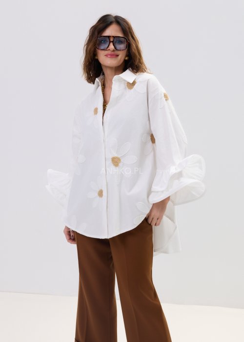 Biała koszula damska oversize z haftowanymi stokrotkami i szerokimi, falującymi rękawami.