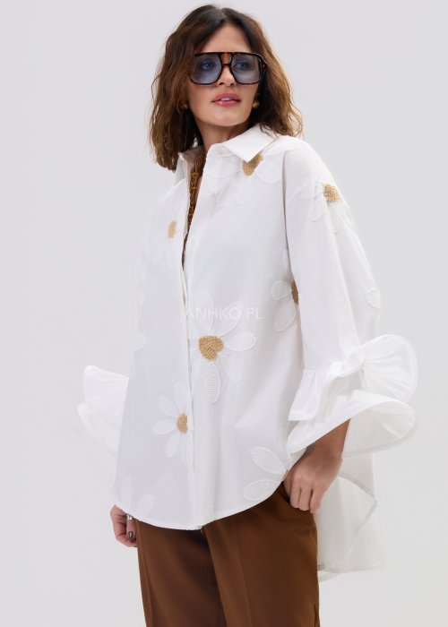 Biała koszula damska oversize z haftowanymi stokrotkami i szerokimi, falującymi rękawami.