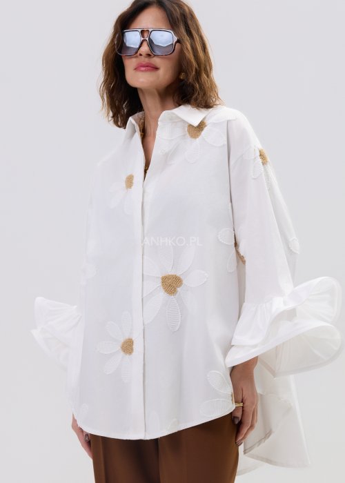 Biała koszula damska oversize z haftowanymi stokrotkami i szerokimi, falującymi rękawami.