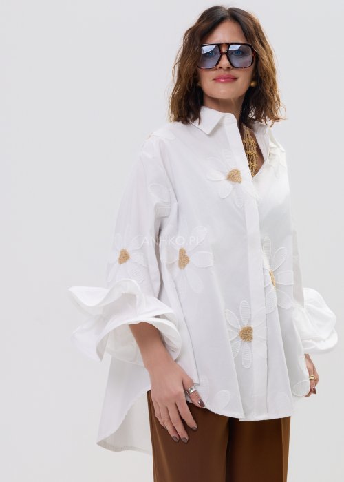 Biała koszula damska oversize z haftowanymi stokrotkami i szerokimi, falującymi rękawami.