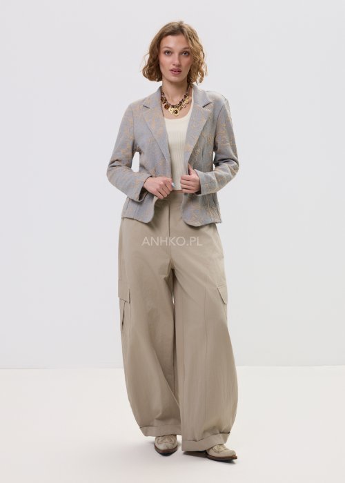 Beżowo-szary żakiet damski w delikatny roślinny wzór, zapinany na guziki, z klasycznymi klapami i prostym fasonem. Elegancka marynarka w stylu smart casual zestawiona z jasnymi spodniami cargo.