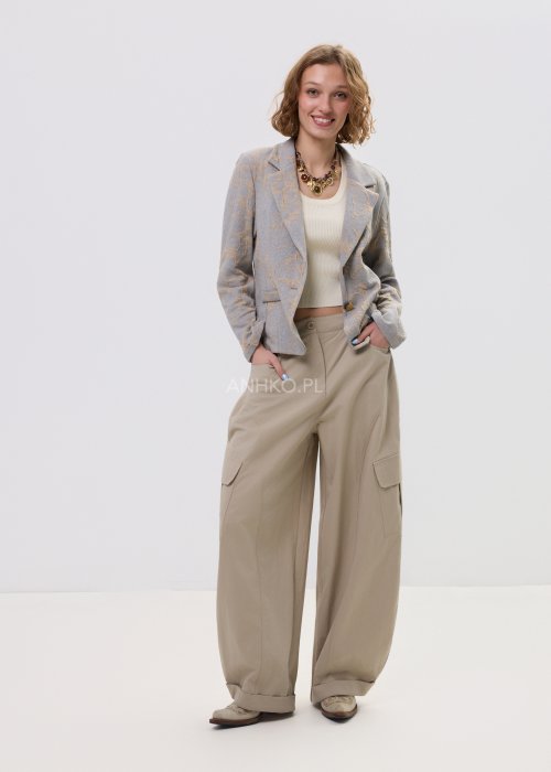 Beżowo-szary żakiet damski w delikatny roślinny wzór, zapinany na guziki, z klasycznymi klapami i prostym fasonem. Elegancka marynarka w stylu smart casual zestawiona z jasnymi spodniami cargo.