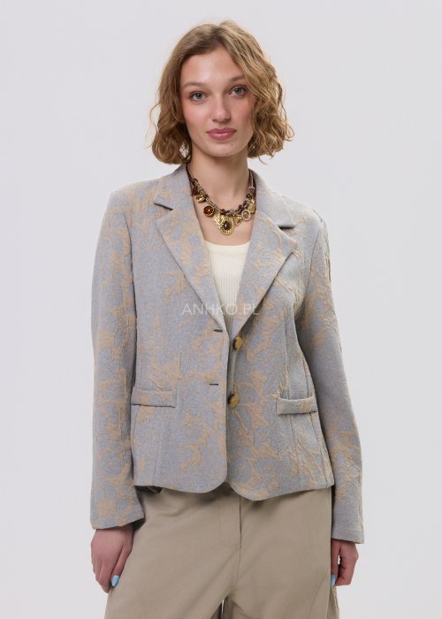 Beżowo-szary żakiet damski w delikatny roślinny wzór, zapinany na guziki, z klasycznymi klapami i prostym fasonem. Elegancka marynarka w stylu smart casual zestawiona z jasnymi spodniami cargo.