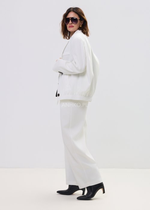 Białe spodnie damskie garniturowe z wysokim stanem, zapinane na guzik, z eleganckimi zakładkami z przodu. Szeroka, lekko zwężana nogawka nadaje im nowoczesny, elegancki charakter.