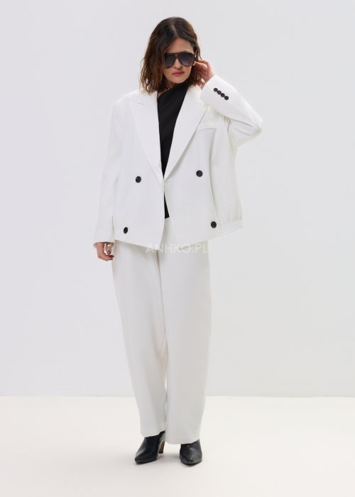 Biała kurtko-marynarka damska o nowoczesnym, lekko oversize’owym kroju, zapinana na guziki, z klasycznymi klapami i kieszenią na piersi.