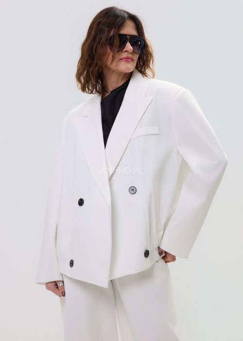 Biała kurtko-marynarka damska o nowoczesnym, lekko oversize’owym kroju, zapinana na guziki, z klasycznymi klapami i kieszenią na piersi.