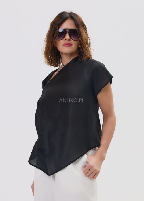 Czarna asymetryczna bluzka damska z lekkiej, półtransparentnej tkaniny, z efektownym drapowaniem na ramieniu i luźnym, swobodnie opadającym fasonem. Stylizacja z jasnymi spodniami.